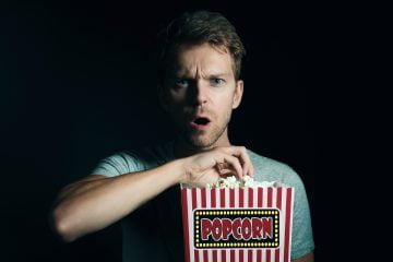 Man eating popcorn. movie trailers coming soon.